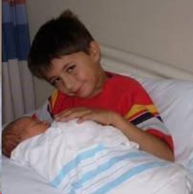 My son, age seven, is holding his baby sister for the first time.